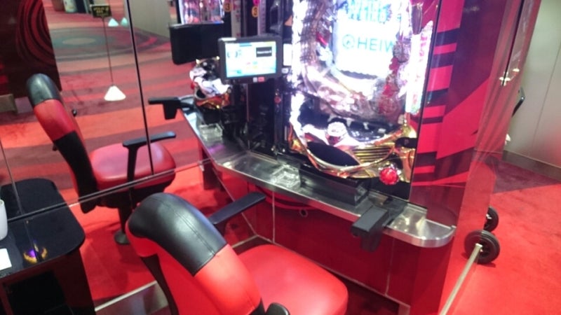 パチンコ実機と赤い椅子が並ぶ店内ブース(人物写らず)
