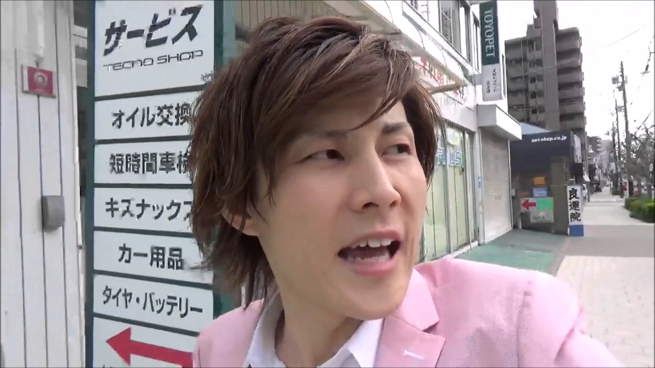 商店街の看板前を歩きながら話す本人（動画「バイクを売る理由」より）