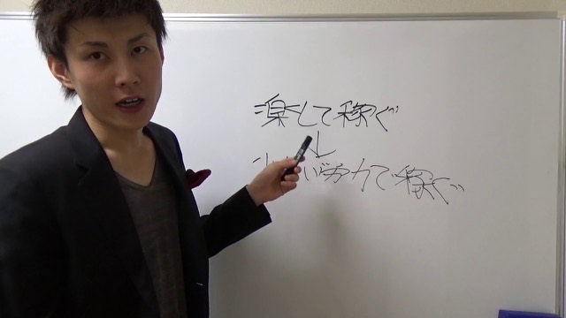 ホワイトボードに「楽して稼ぐ→いい努力で稼ぐ」と書き、ペンで指し示す本人（動画「楽して稼ぐ方法はあるのか？」より）