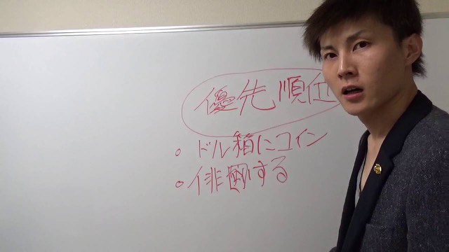 ホワイトボードの「優先順位」を指す本人（動画「優先順位を考えてスピードアップ！【パチスロ】…」より）