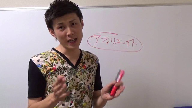 「アフィリエイト」と板書したボード前で赤ペンを持つ本人（動画「無料パチスロサイト、ブログが稼げる理由【パチスロ】…」より）